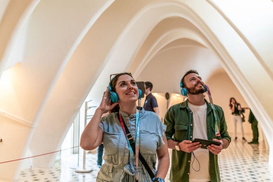 Two travellers following an audio guide on their phones outside Casa Batlló in Barcelona